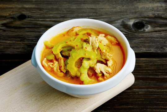 Thai Chicken Curry with Bitter Gourd in white bowl on wooden background.
Chinese bitter melon with coconut and curry soup.