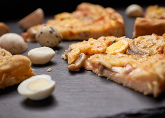 Italian pizza slices, peppers, spices served on a black background