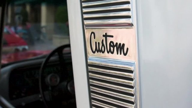 Driver's-side close up, slow-motion pan of a classic C10 pickup Custom logo and B-Pillar trim work from a Florida car show.