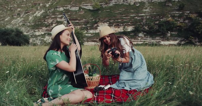 Beautiful girls have a picnic time in the middle of mountain landscape, taking pictures and have a great time