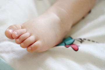 Closeup new born little baby feet.Baby on white bed 