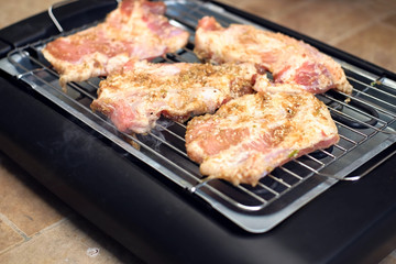 Delicious pieces of meat with spices on the electric grill.