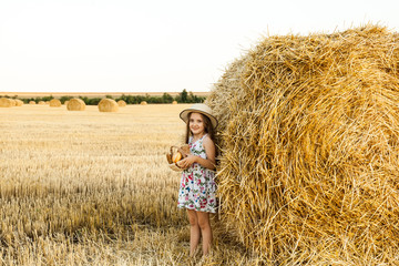 Naklejka na ściany i meble Happy girl on field of wheat with bread