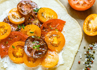 Preparation of summer Pai with cottage cheese, multi-colored (red, pink, orange, yellow, black) tomatoes and thyme. Delicious Galette