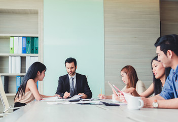 Group of business partners discussing ducuments and ideas at meeting.