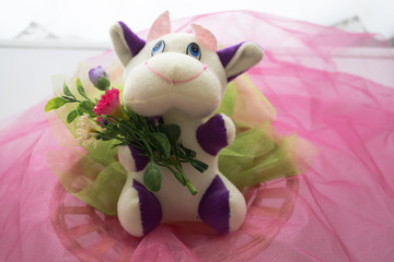 Soft cow toy with flowers on pink background