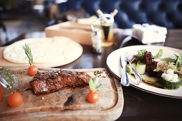 steak in the restaurant on the table / dinner in the restaurant, meat on the plate, served steak and cutlery