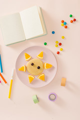 Fun with food concept - Child cooking and eating funny breakfast lion pancake with orange