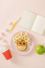 Baby pancakes for breakfast. Creative idea for the kid dessert: delicious pancakes in the form of the happy face with the hair making popcorn