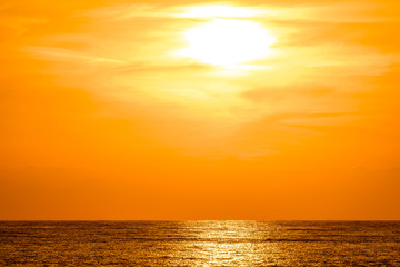 Fototapeta na wymiar Orange sunset with golden reflection on sea. Light of setting sun shimmering on the ocean surface.