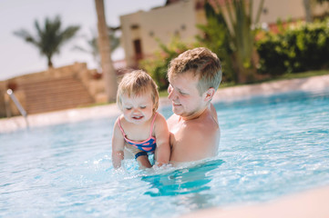 Fototapeta na wymiar father teacing baby to dive in swimming pool