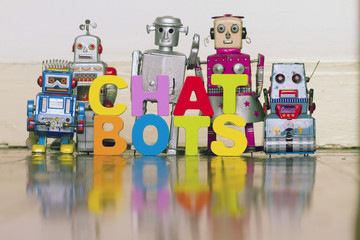 Obraz premium the word CHAT BOTS with5 retro robots on a wooden floor