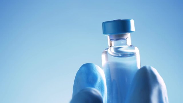 Doctor in blue latex gloves holding glass vial with medicine