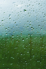 Fototapeta na wymiar Natural background Drops on both sides of the glass from the rain and from the fogging abstract view, raindrops against the blue glass and the blurred landscape of the gradient of blue and green