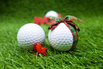 golf with Christmas ribbon and heart are on green grass