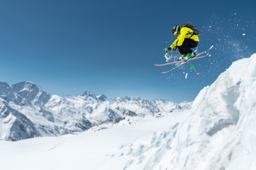 A skier in full sports equipment jumps into the precipice from the top of the glacier against the...