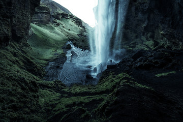 A wild natural fresh sparkling waterfall in a lonely green valley with moos covered rocks and ice...