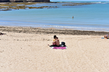 Couples enjoying sunbath at Caleta Beach in Cadiz, Spain