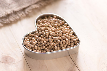 Soybeans in a heart shape plate on wooden background, alternatime source of protein for vagetarian