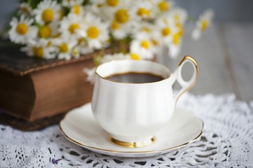 Composition with cup of coffee,flowers and book on the table 