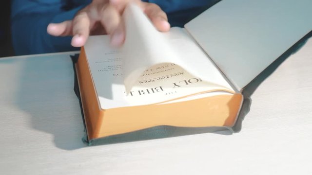 Holy Bible. Man preacher praying to God with his hands resting on a bible slow motion video. the man is reading a book Holy Bible in church. concept for lifestyle faith spirituality holy bible and