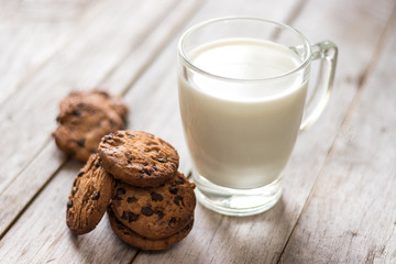 Chocolate chips cookies and a glass of milk on wooden background, homemade sweet and dessert concept