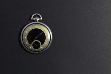 Obraz na płótnie Canvas Closeup of a beautiful retro style black and silver pocket watch on black background.