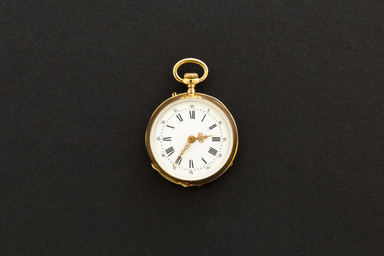 Closeup of a beautiful classic gold pocket watch on black background.