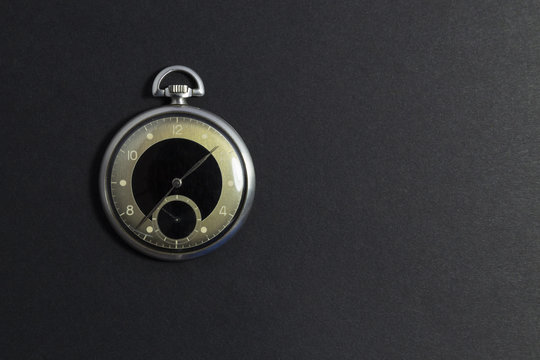 Closeup of a beautiful retro style black and silver pocket watch on black background.