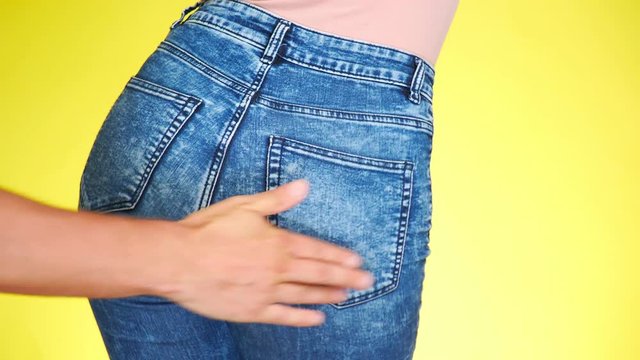 a male hand slaps the girl's buttocks. the girl in jeans seductively moves. 4k, close-up. slow-motion