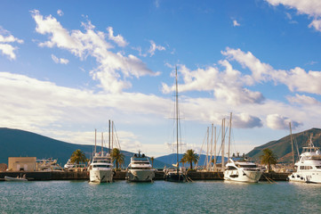 Fototapeta na wymiar Beautiful landscape with blue sky, white clouds and line of yachts. Montenegro, Tivat, view of yacht marina of Porto Montenegro