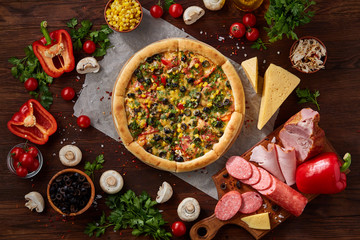 Pizza still life. Part of freshly baked pizza and its components arranged on wooden background.