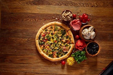 Pizza still life. Part of freshly baked pizza and its components arranged on wooden background.