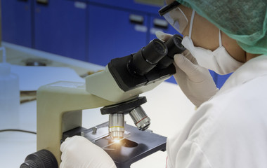 Scientist looking through a microscope in a laboratory. she is doing some research