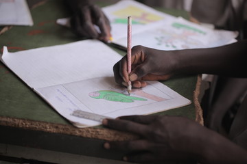 african education close up - macro photography of a black african school kid hand holding a pencil,...