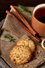 Christmas teatime with oatmeal, chocolate biscuits, and spices, on wooden background, close-up, selective focus.