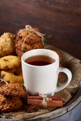 Christmas teatime with oatmeal, chocolate biscuits, and spices, on wooden background, close-up, selective focus.