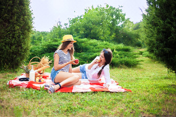 Two beautiful young girls at a summer picnic eating apples