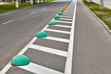 Cycle track or bikeway with markings on roadway, hemispheres fenced.