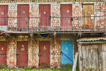 Fototapeta na wymiar Painted rusty old warehouse doors on two-storey brick building.