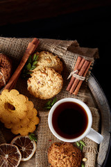 Cookies with cinnamon and two cups of tea on a burlap napkin, selective focus, close-up, top view.