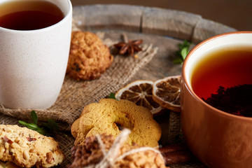 Traditional Christmas tea concept with a cup of hot tea, cookies and decorations on a wooden background, selective focus