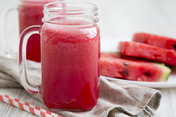 Glass jars of watermelon smoothie on a white wooden background, side view. Closeup.