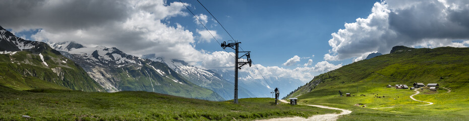 a view of the chamonix valley from the alpine mountains in the Vallorcine area with foreground of alpine meadows on a clear summer day with blue sky and bright clouds