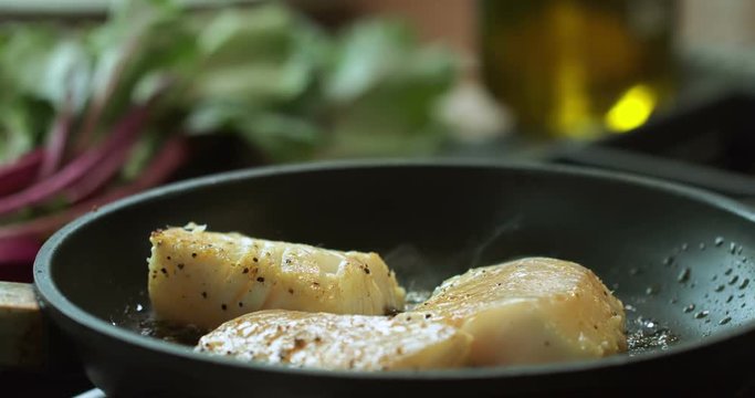 Professional chef in a modern restaurant is preparing cod fillet