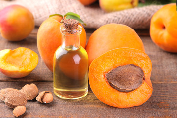 Apricot seed oil next to fresh apricots on a brown background