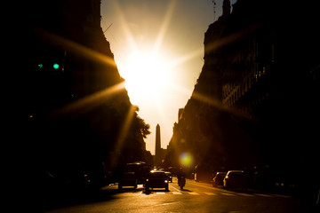Avenue with solar backlight and obelisk of Buenos Aires in the background