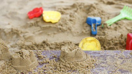 Fototapeta na wymiar children's toys are scattered in the sandbox. Blade, rake, pail for building a sand tower