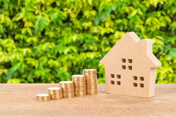 Model house and coin stack on green tree background mortgage saving concept