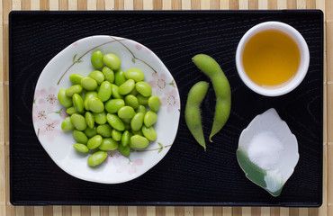 Green Japanese Soybeans in plate ,Green Tea and Salt on Black Tray